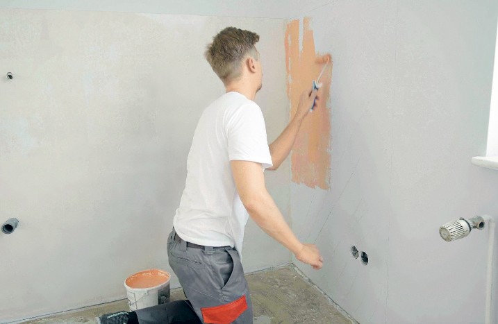 Ein Handwerker trägt Grundierung an einer Wand auf.